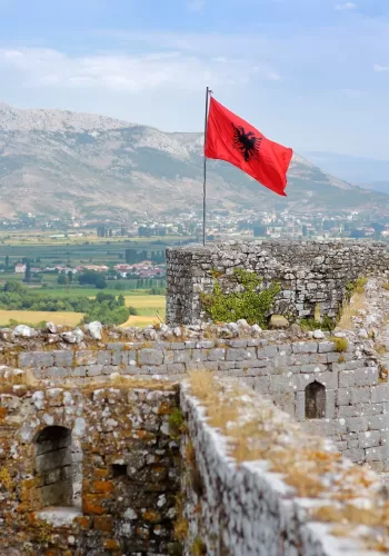 Red Albanian flag with black eagle waving over wall of Fortress Rozafa near Shkodra city